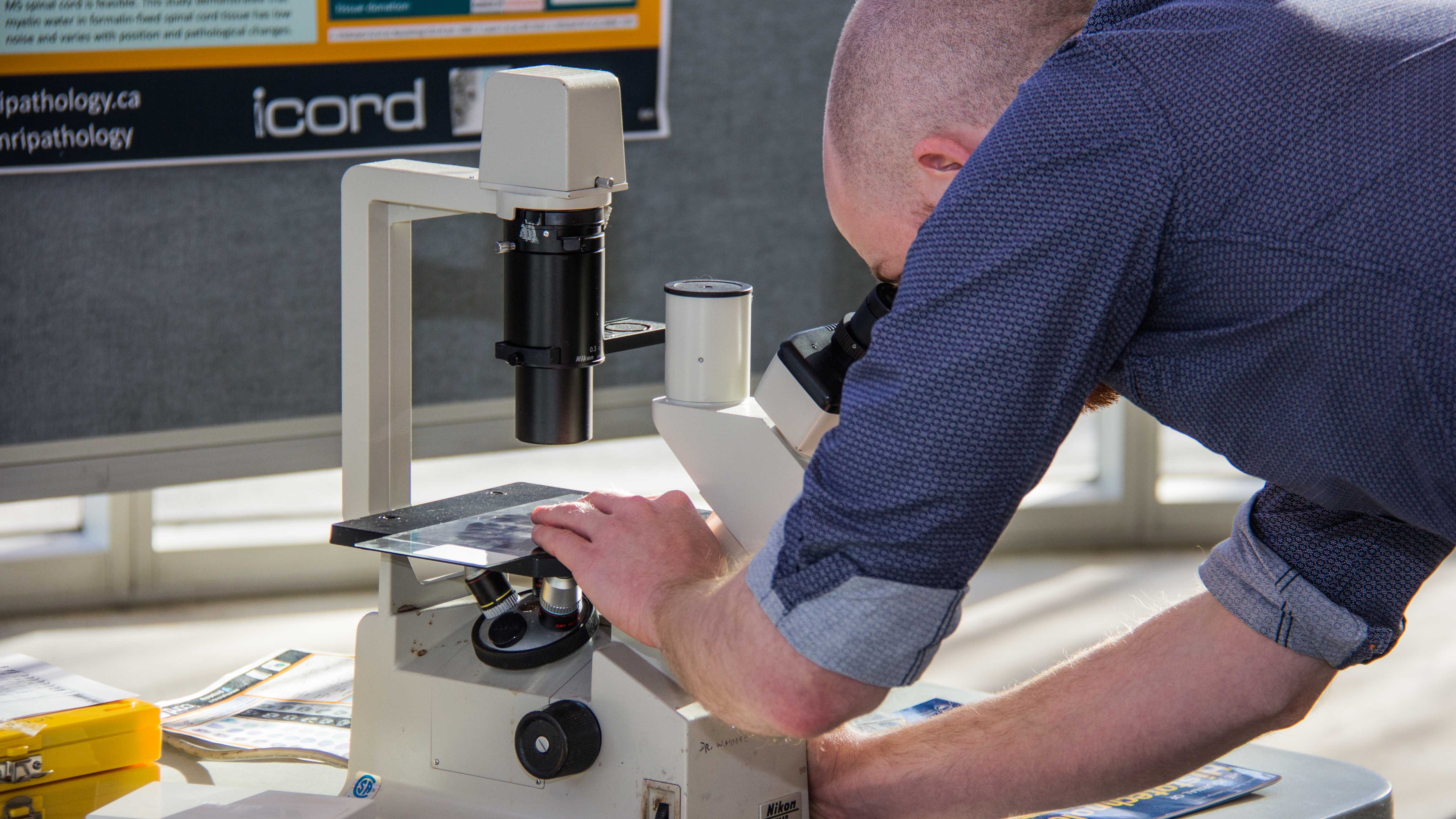 man leans over microscope