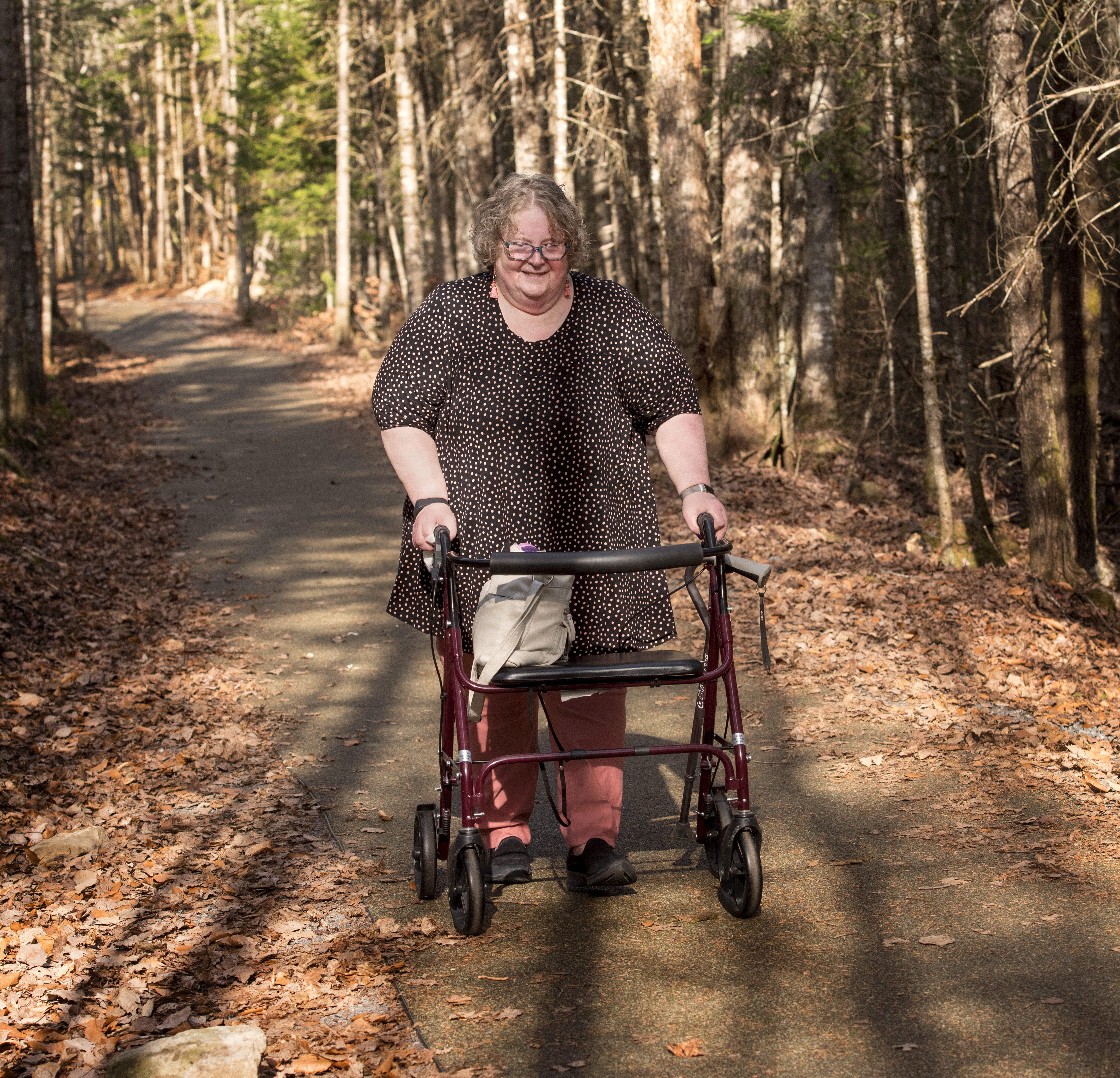 A woman navigates an accessible outdoor trail using a walker