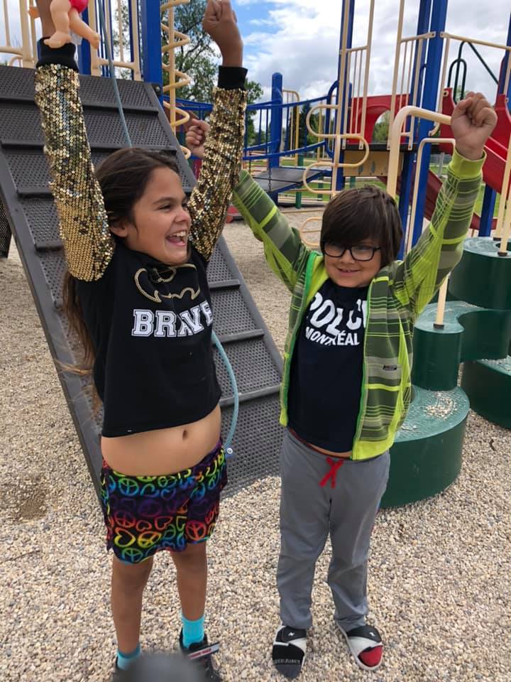 Simon and his sister in a playground, arms raised