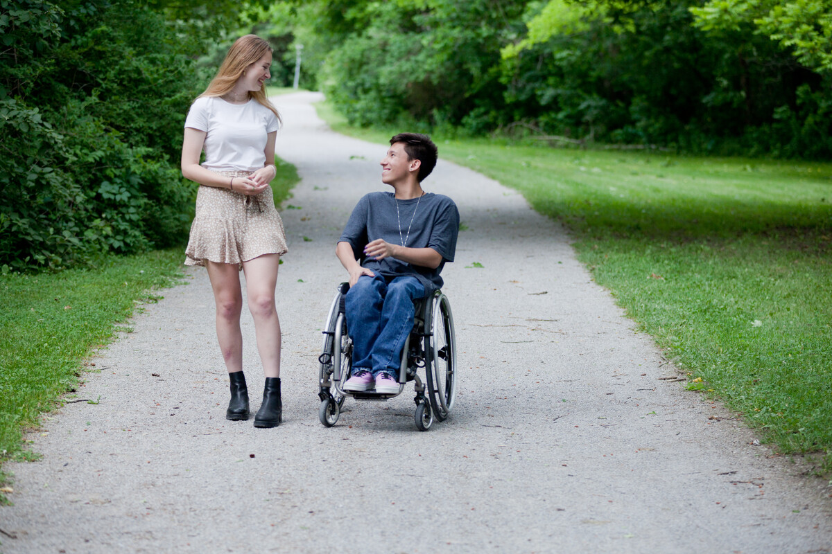 Tai laughing with his friend, Sam as they proceed down an accessible pathway.