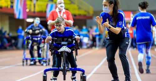 Veronique Messier cheering on a student who is racing and using an assistive walking device.