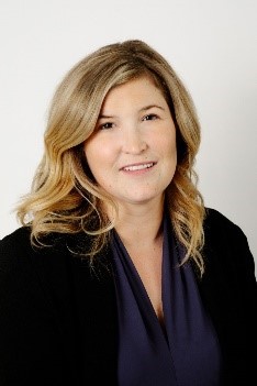 Woman with blonde hair smiling against plain background