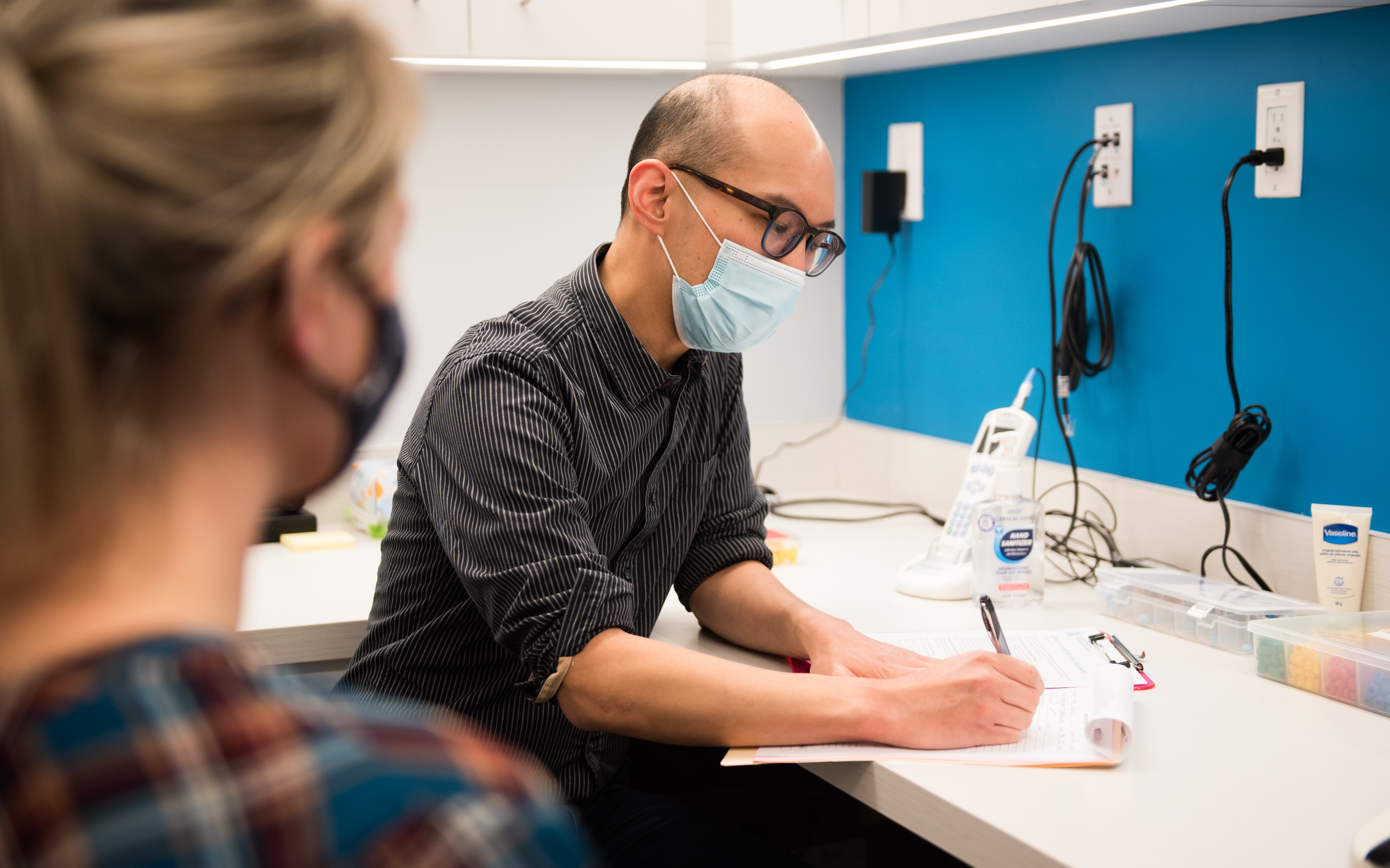 audiologist and patient, both wearing masks