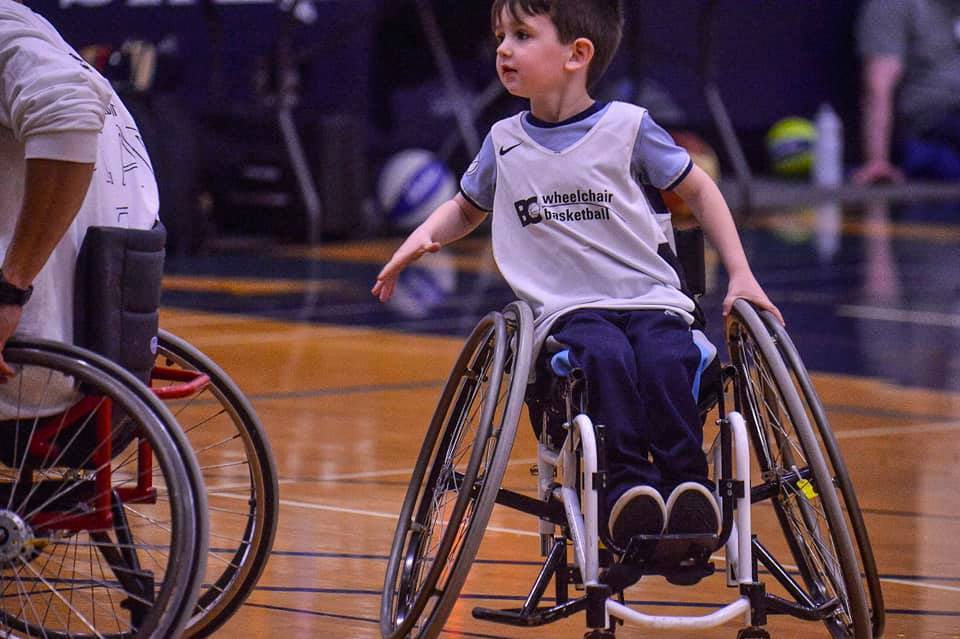 Young boy in wheelchair playing basketball.