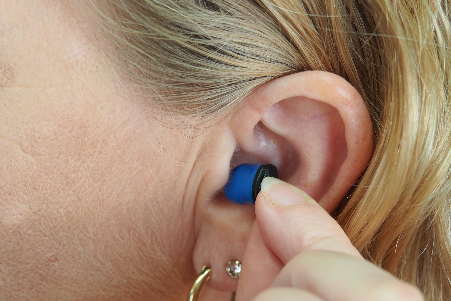 Woman putting a hearing aid on.