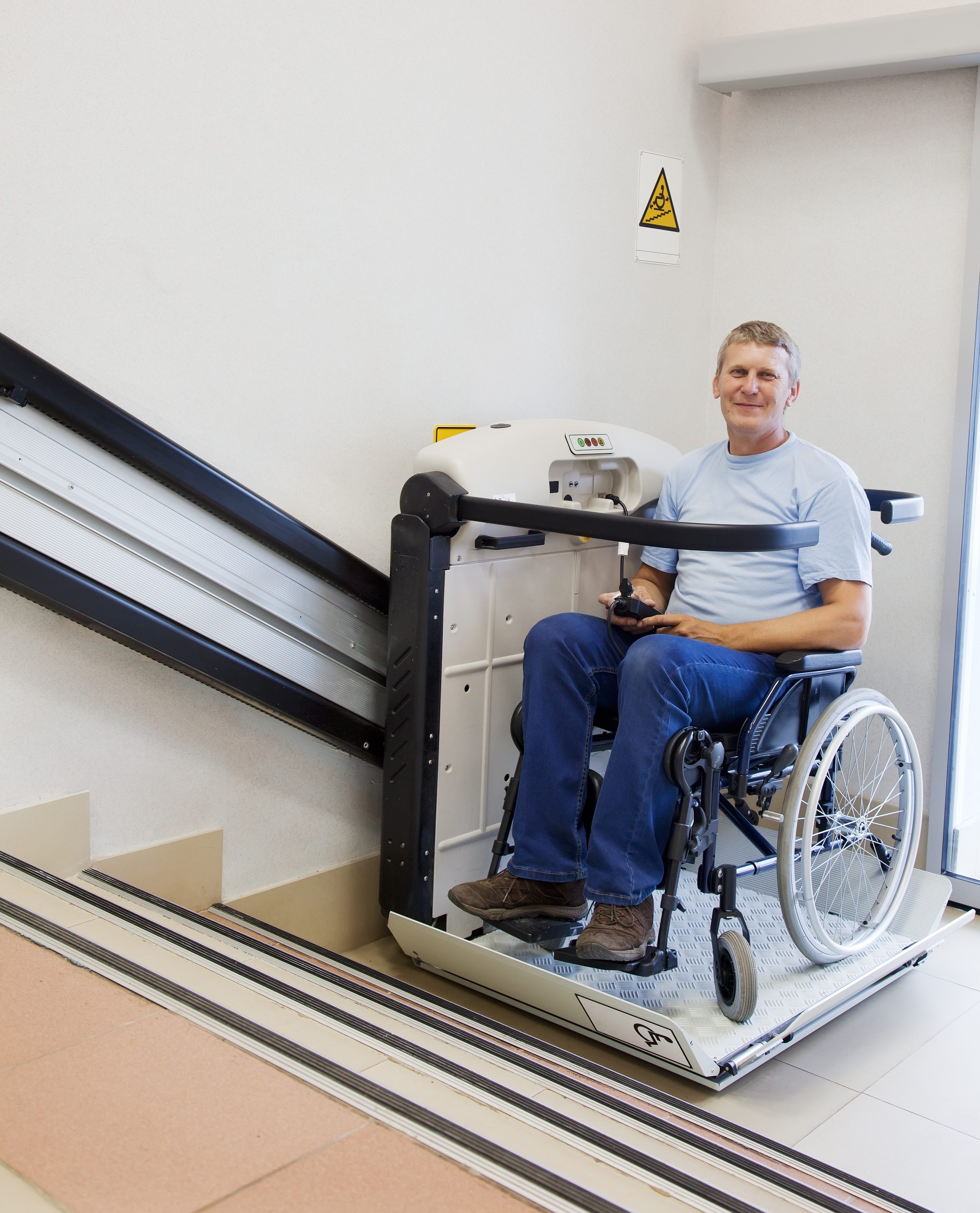 man using an accessible chair lift to go up the stairs.