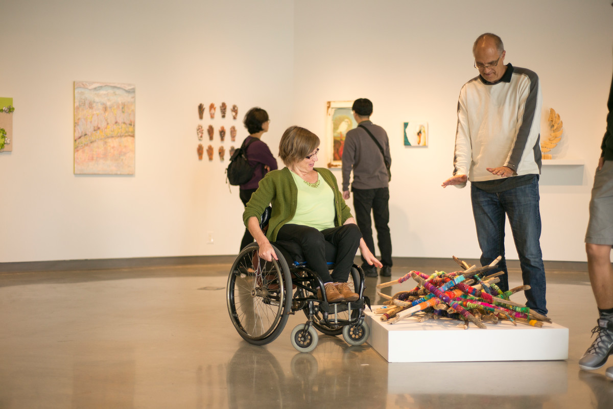 Woman using a wheelchair observes art in an accessible gallery