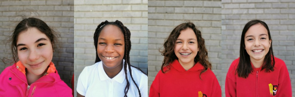 four young girls in a line with a brick wall in the background