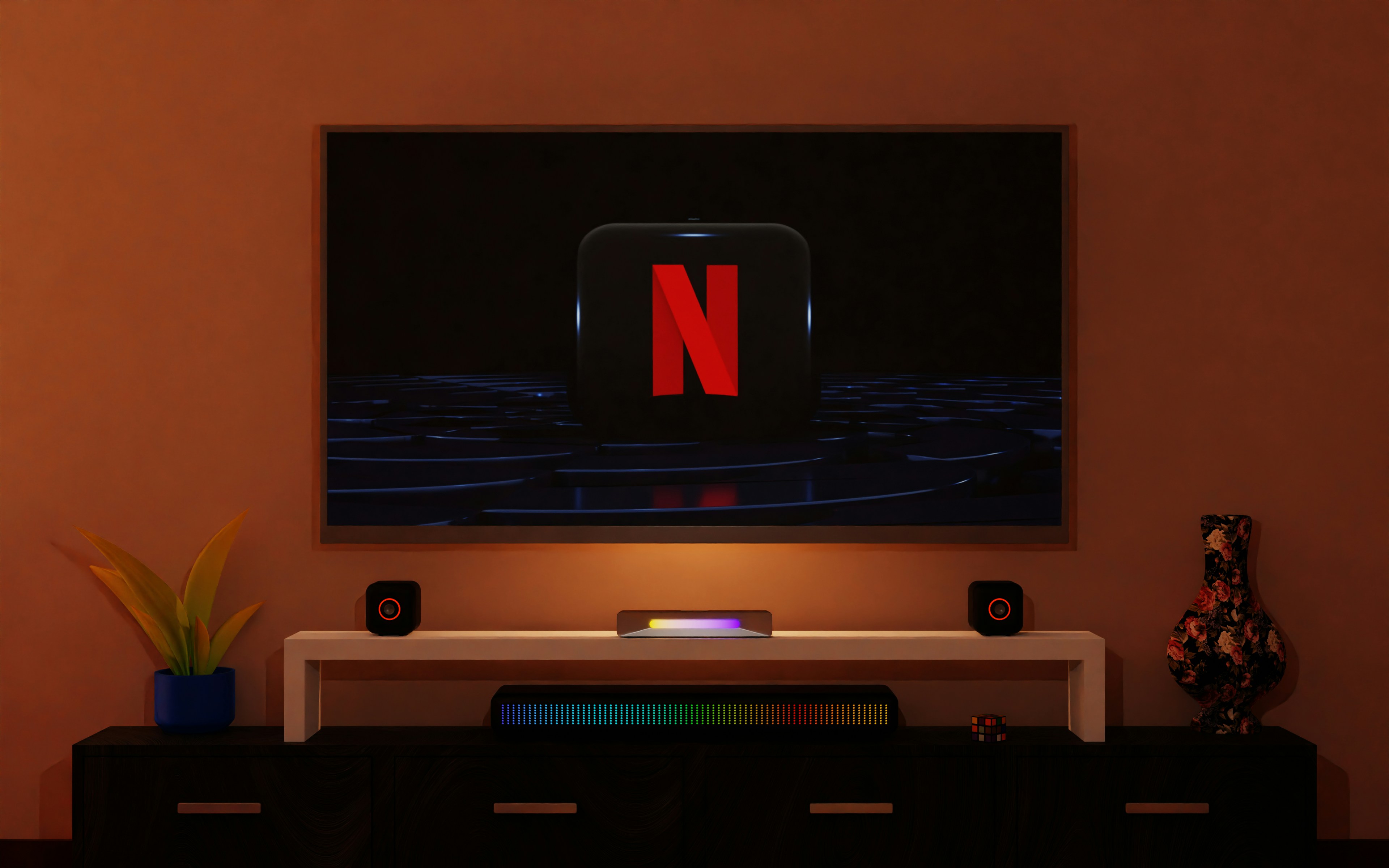 An image of a TV on a wall with the Netflix letter "N" logo on the screen. There is a table underneath with tiny square speakers on both sides. The image is in a dimmed room.
