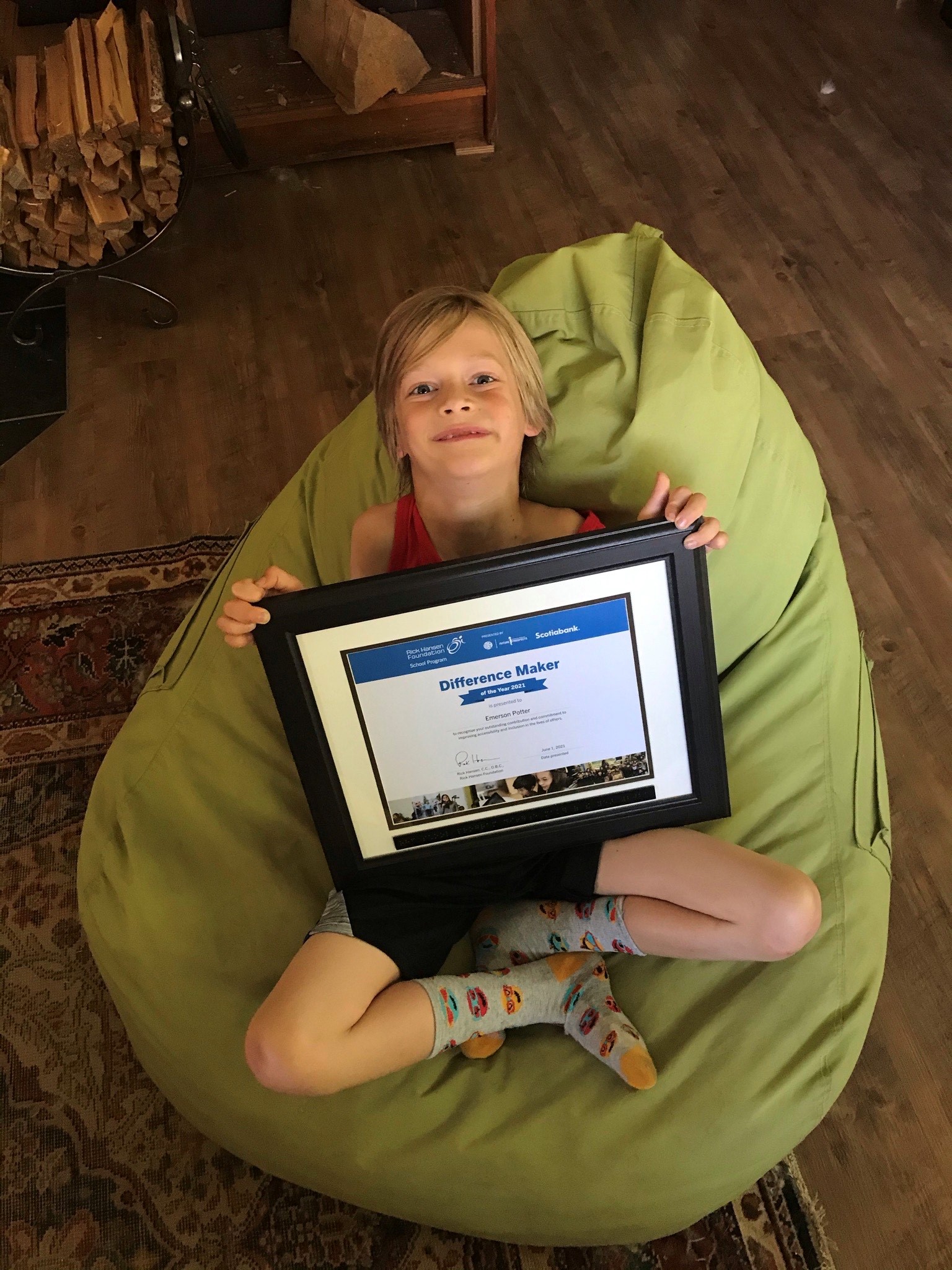 young boy lies in a beanbag chair with an award certificate