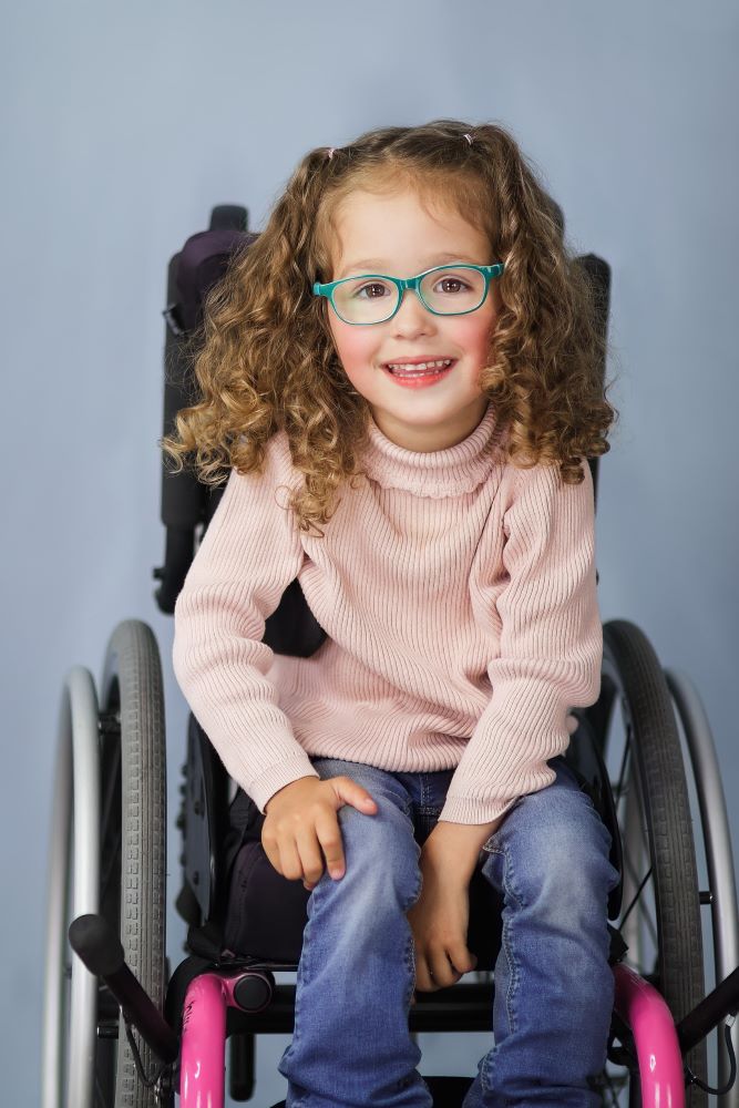 Holland, who has curly brown hair, green glasses and is using a wheelchair.