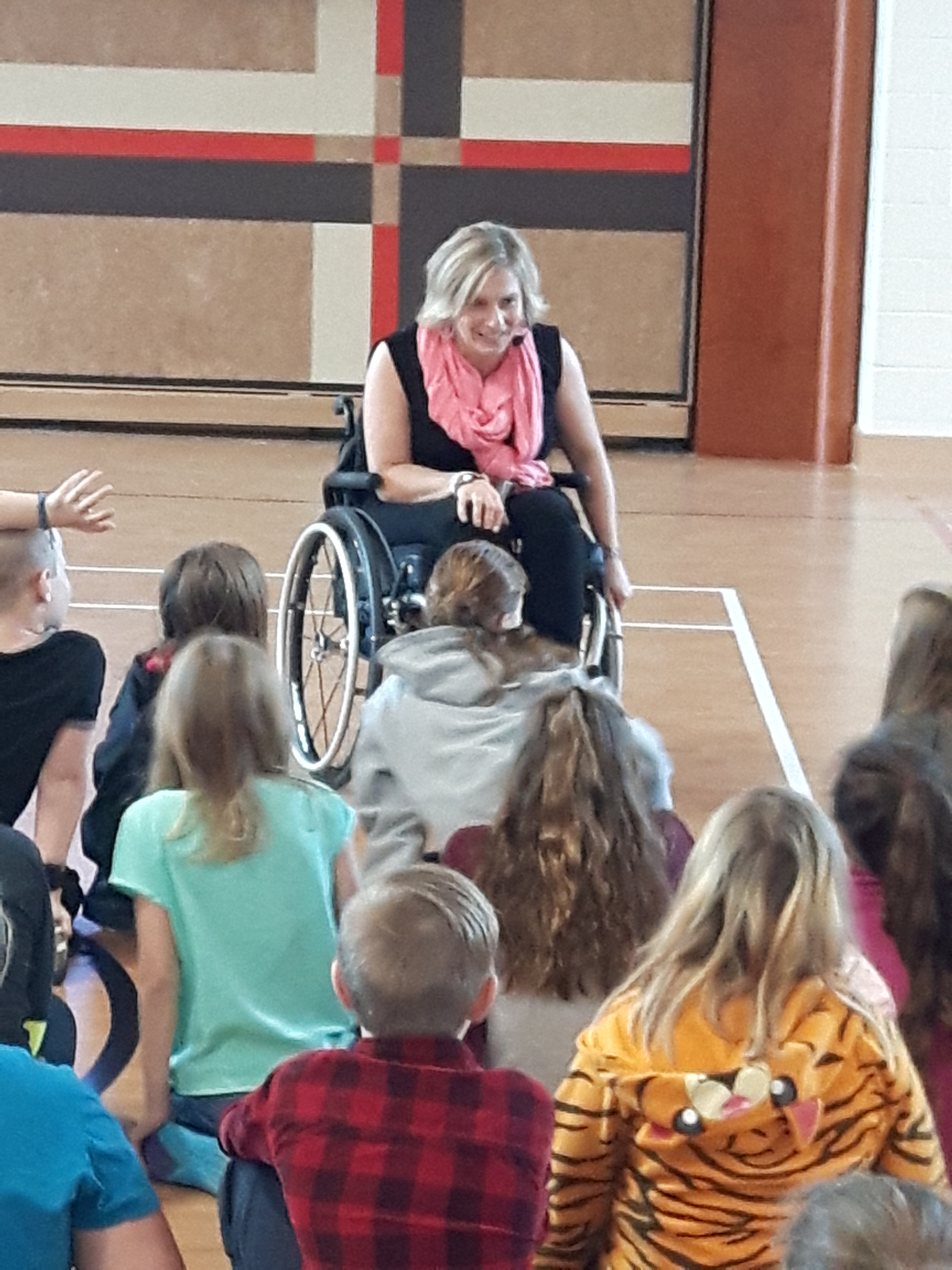 Julie speaks to students in a school gymnasium 