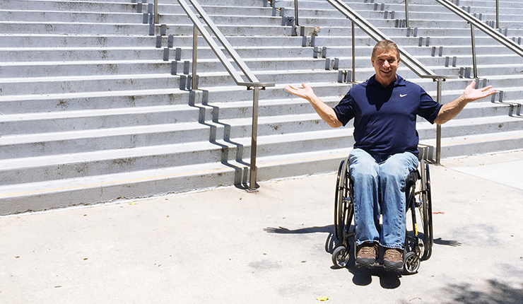 Rick Hansen smiles in front of a staircase. 