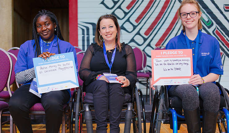 3 young woman smiling holding a pledge sign about making a difference. 