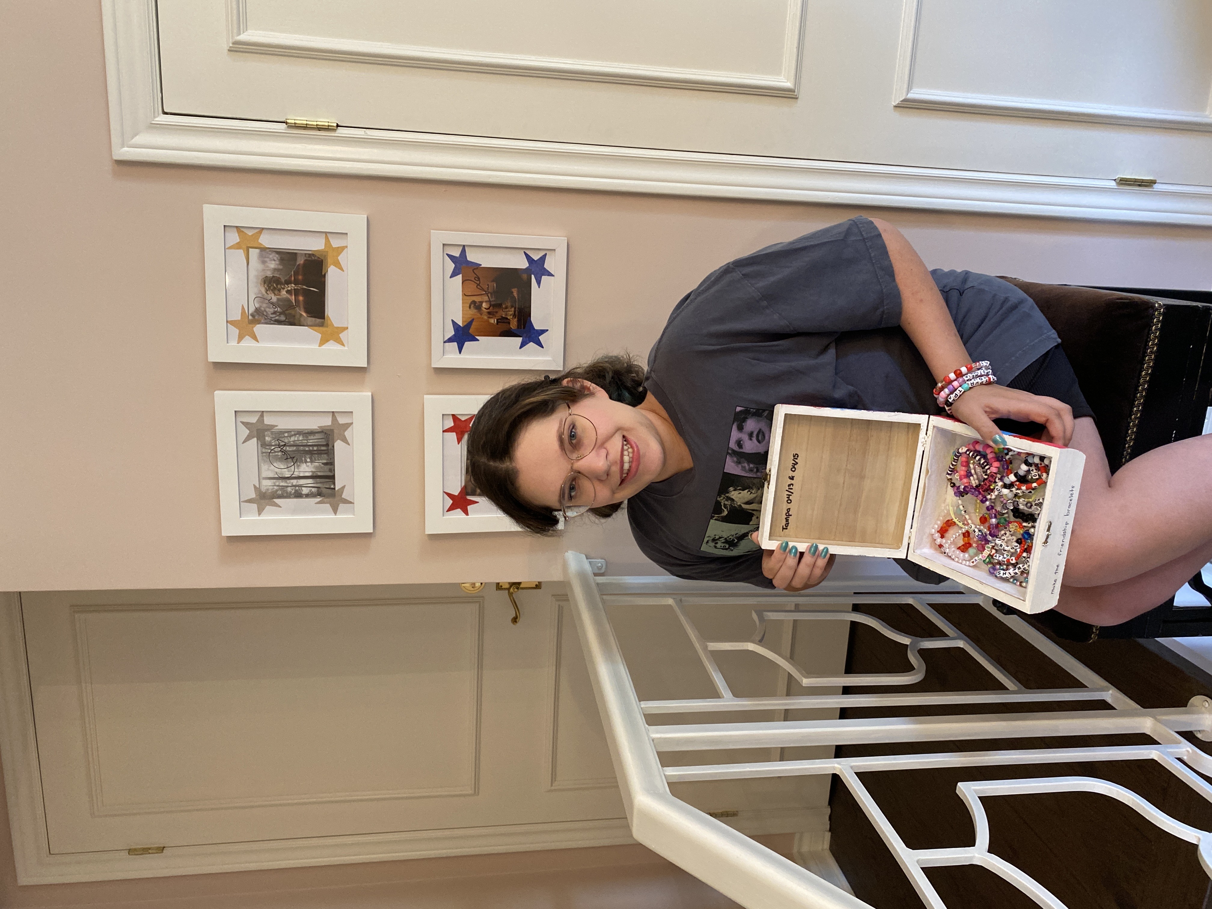 A young woman with brown hair with a small keepsake box full of friendship bracelets from the Taylor Swift Eras Tour.