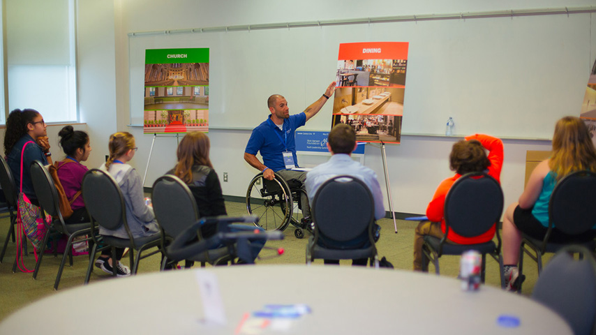 Man in wheelchair giving a talk to the audience.