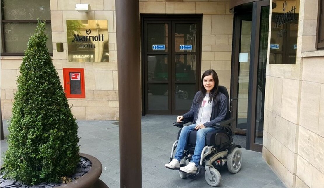 Woman is outside the hotel as she assesses hotels for wheelchair accessibility