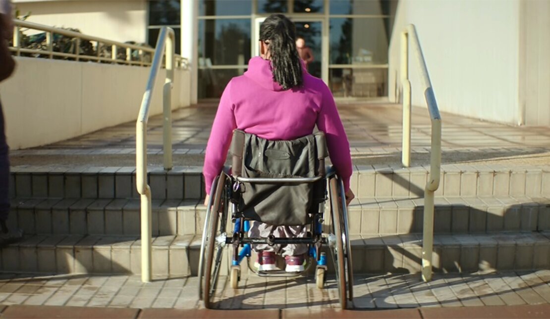 Djami Diallo in a wheelchair in front of stairs
