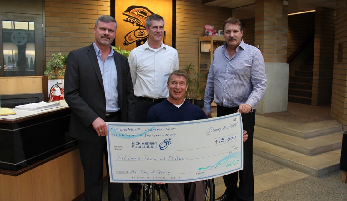 Rick Hansen holding cheque with company donors for $15,000