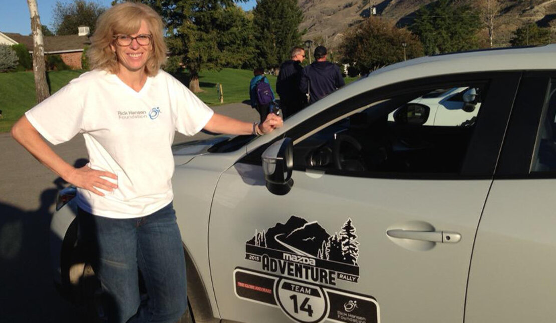 Women poses by car as she drives through B.C. to drive donations to the Rick Hansen Foundation