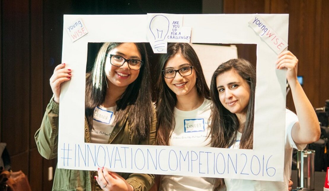 Three ladies pose in a rectangle picture frame at the Innovation Competition in 2016