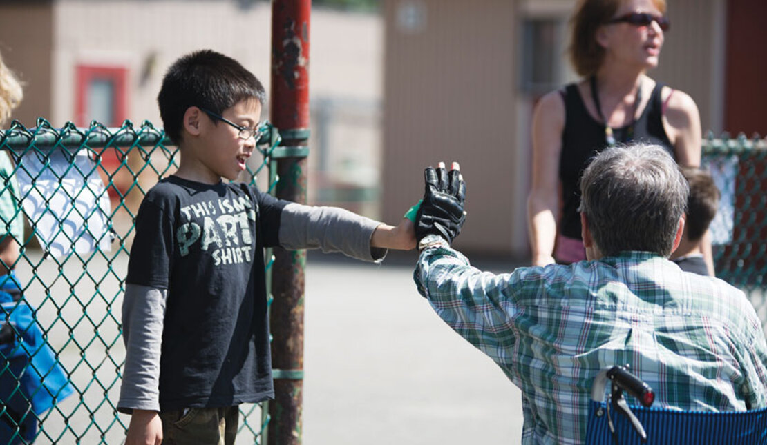 Child and man in a wheel chair hi-five's at school 