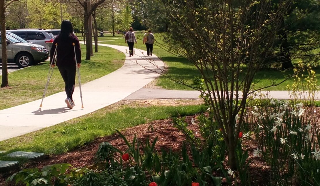 Woman with crutches walks along the path