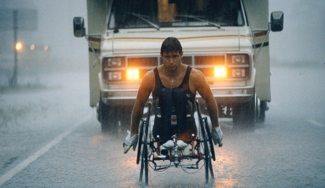 Rick Hansen wheeling through rain during Man in Motion World Tour