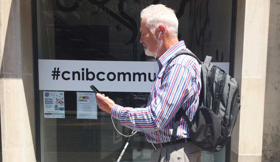 Man with vision loss uses BlindSquare Enabled Project while walking street in Toronto, Ontario