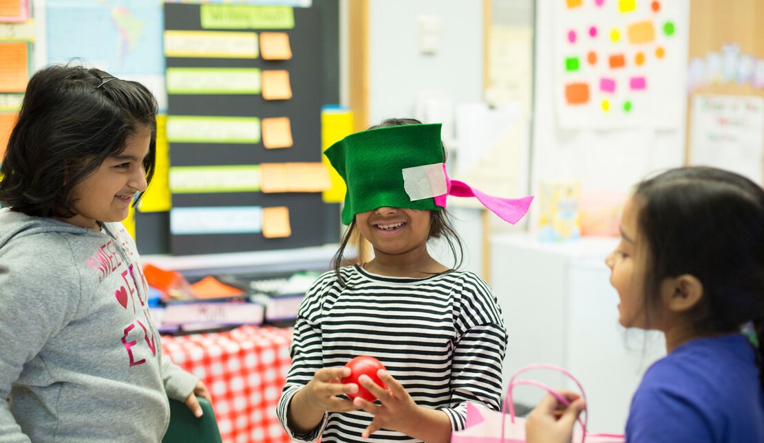 Child with blindfold surrounded by other children 