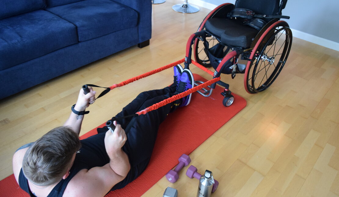 Marco on yoga mat pulling wheelchair using exercise bands 