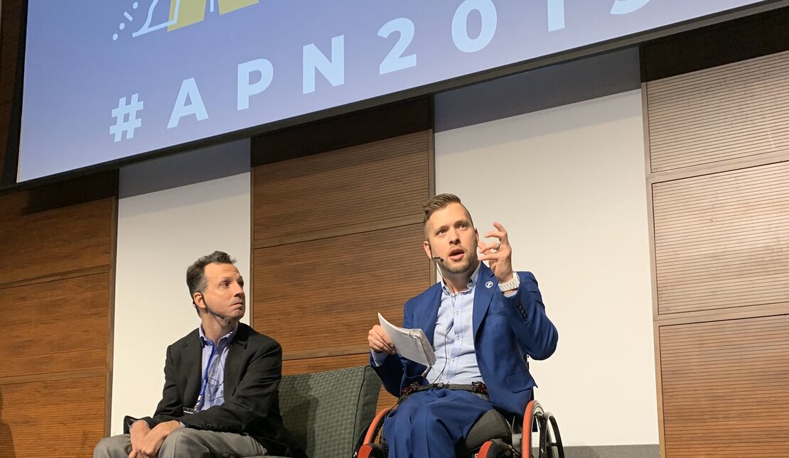 Marco Pasqua on stage using a wheelchair with a guest speaker