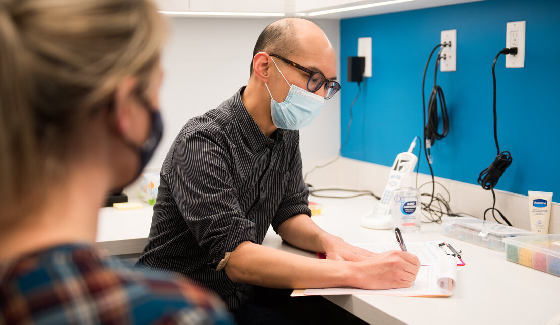 audiologist and patient, both wearing masks