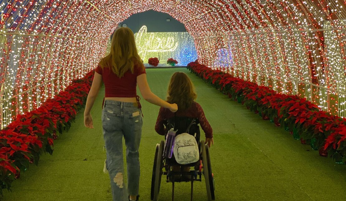 two young girls in a red and white tunnel of lights, one using a wheelchair