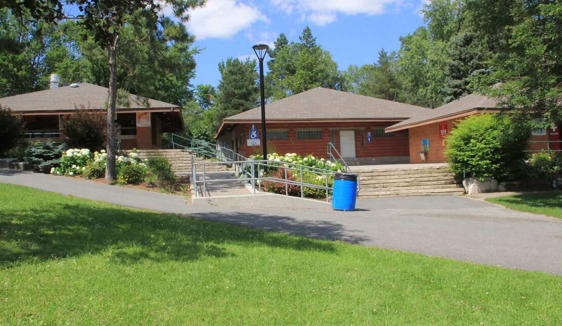 Brick building with accessible wheelchair ramp. The building is surrounded by green grass and trees.