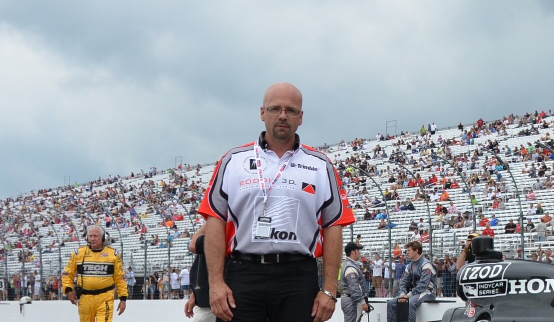 Murray Roddis standing in front of a race car on a track. 