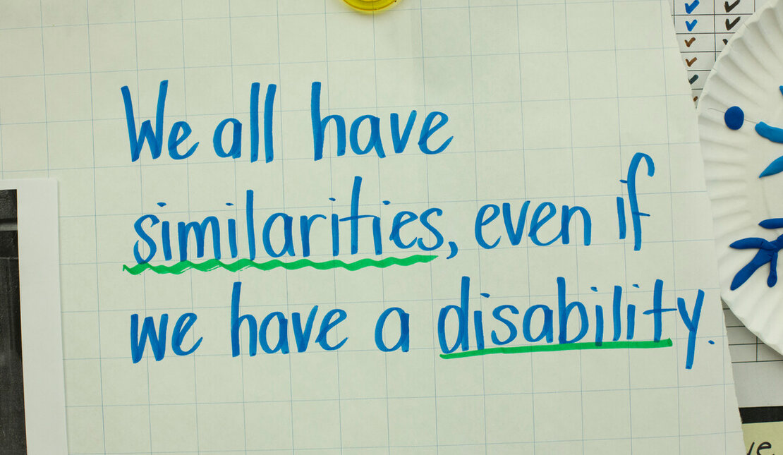 Blue ink on large paper that reads "We all have similarities, even if we have a disability." The words similarities and disability are underlined in green.