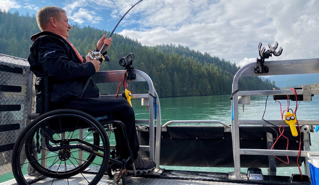 Side profile of Rick Hansen fishing from the back of a boat.