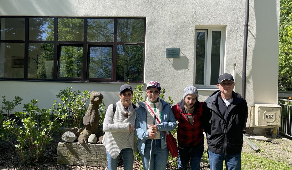 Rachel Ganz and her family standing outside of a building. Rachel is holding a red and white cane.