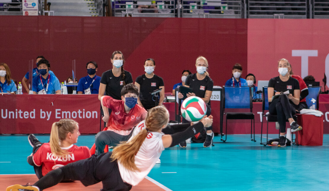 Jolan Wong playing sitting volleyball for Team Canada. She is diving for the ball.