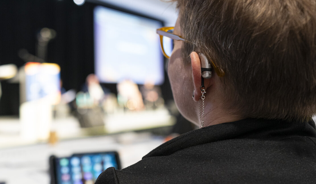 Rear view of a woman with a visible hearing aid behind her ear