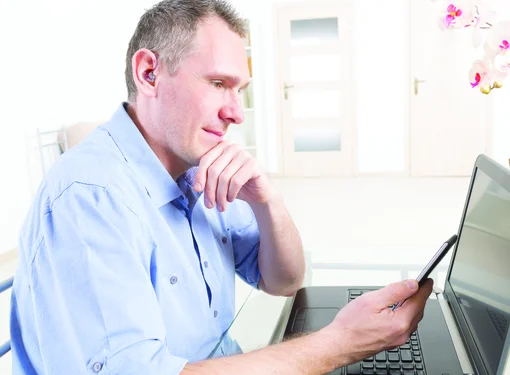 Hard of hearing man uses the computer and phone