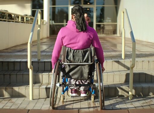 Djami Diallo in a wheelchair in front of stairs
