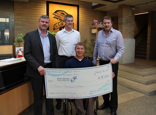 Rick Hansen holding cheque with company donors for $15,000