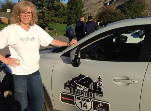 Women poses by car as she drives through B.C. to drive donations to the Rick Hansen Foundation
