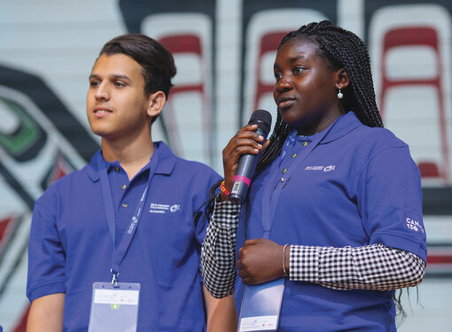 A teenaged boy and girl wearing blue Rick Hansen Foundation polo-shirts presenting at an event. The girl is holding a microphone. Cover image for the Personal Leadership toolkit.