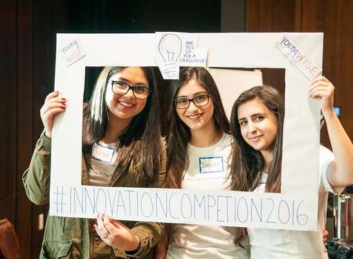 Three ladies pose in a rectangle picture frame at the Innovation Competition in 2016