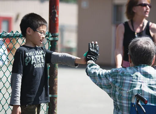 Child and man in a wheel chair hi-five's at school 