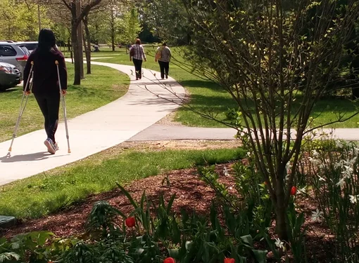 Woman with crutches walks along the path