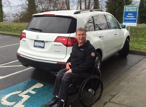 Rick Hansen by an accessible parking space outdoors